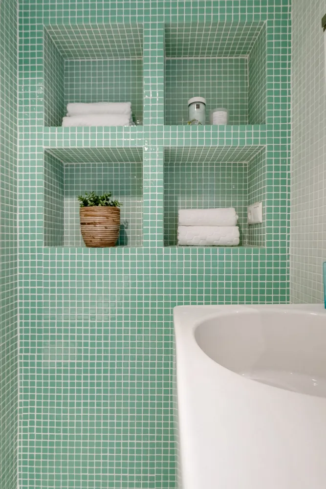 Bathroom with green tiles shelves and towels
