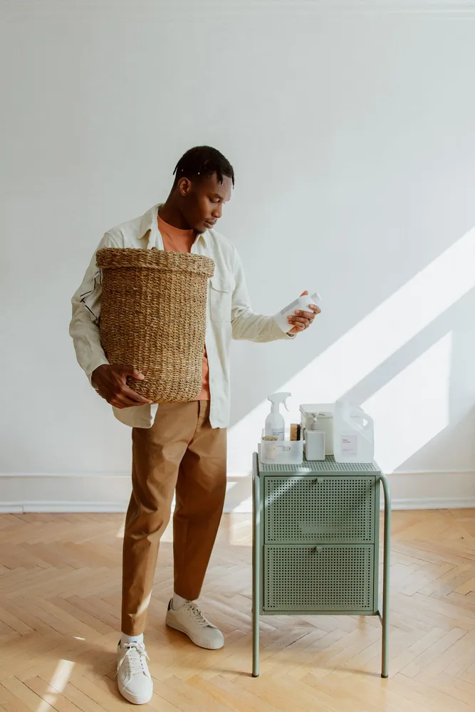 Person holding a laundry basket and reading a cleaning-product label