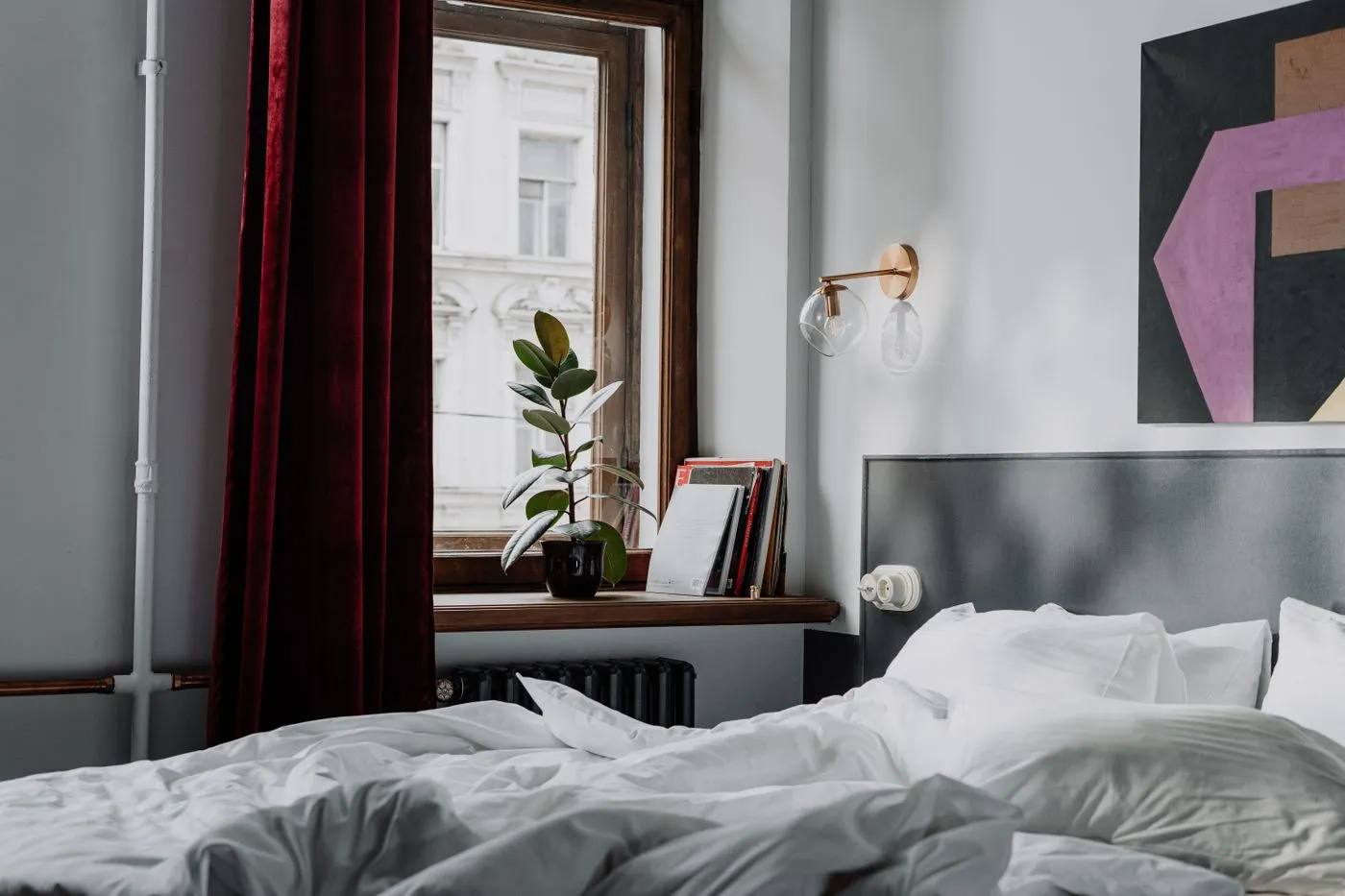 White bed linen beside a red curtain