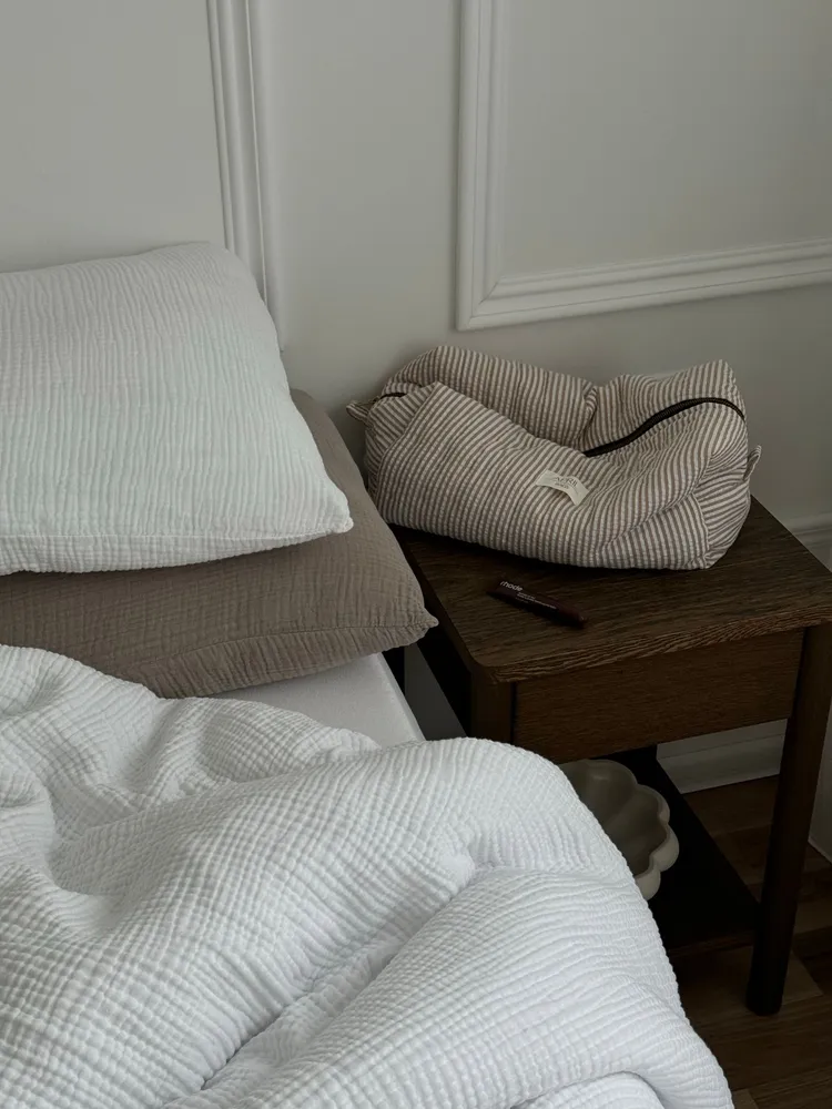 Bed with pillows beside a wooden nightstand