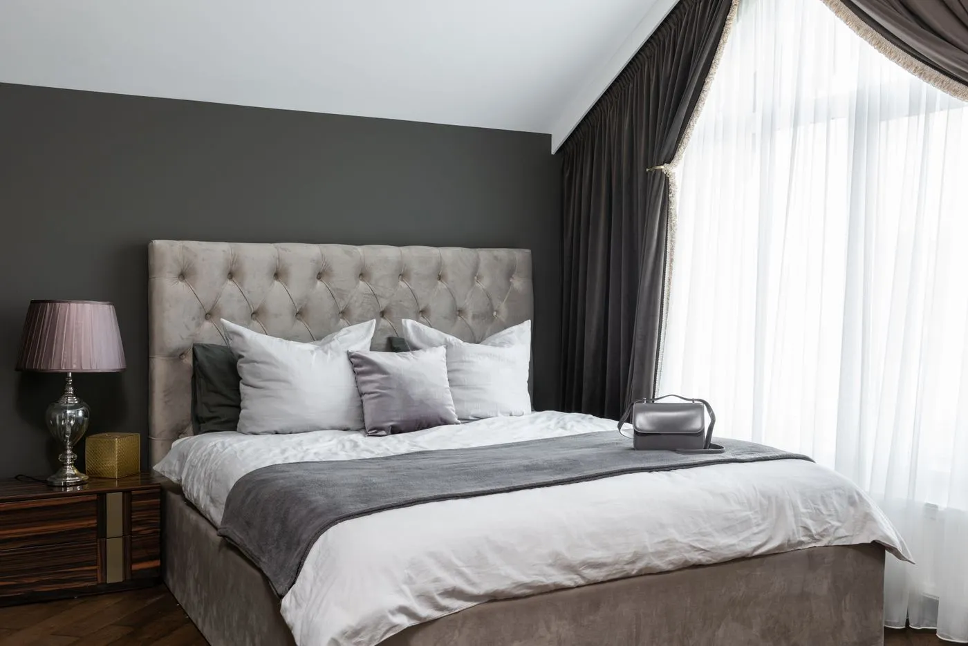 Bed with pillows beside a window and lamp