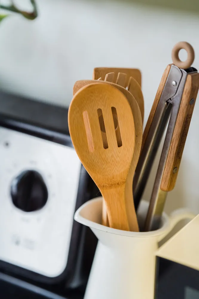 Wooden and metal utensils in a container on a kitchen countertop