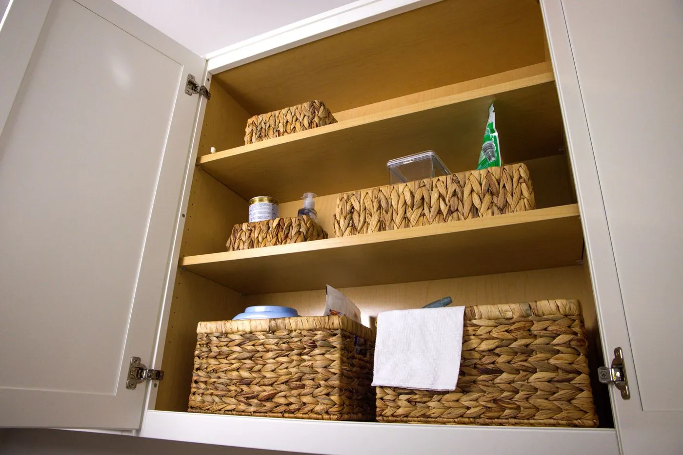 Wicker storage baskets inside a kitchen cabinet